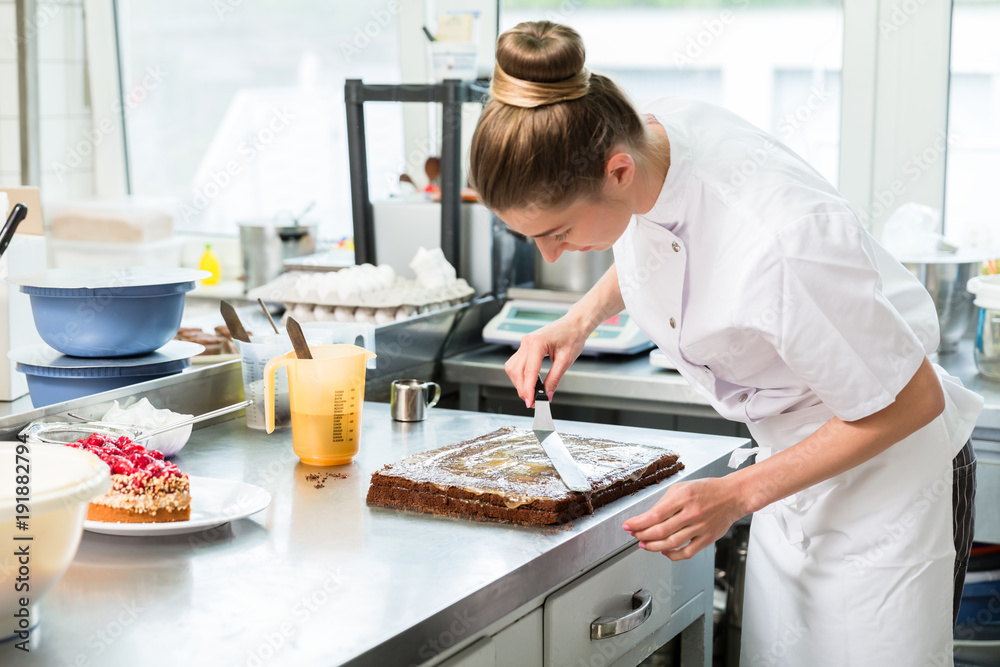 Confectioner woman getting chocolate cake ready with topping put on Confectioner woman getting chocolate cake ready with topping put on