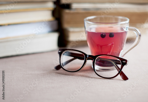 Blueberry tea in glass cap with eyeglasses on the background of books