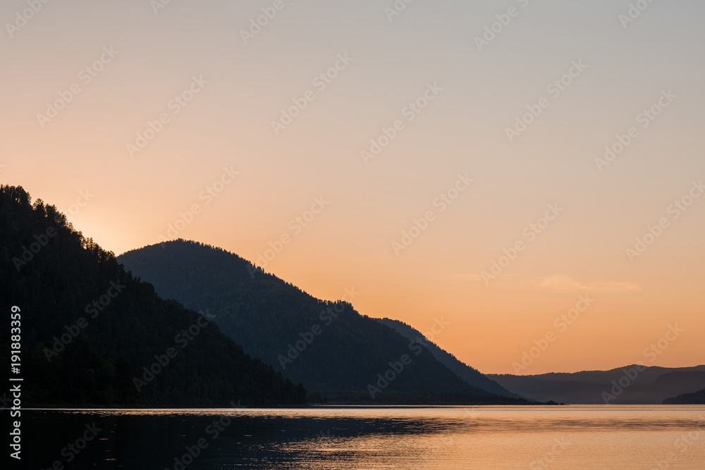 Beautiful mirror surface of a mountain lake at sunset with a warm and level sky