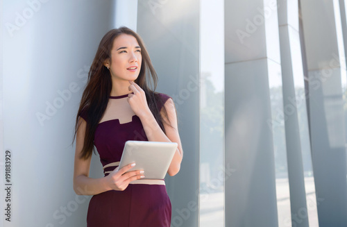 Pensive young businesswoman with tablet outdoors