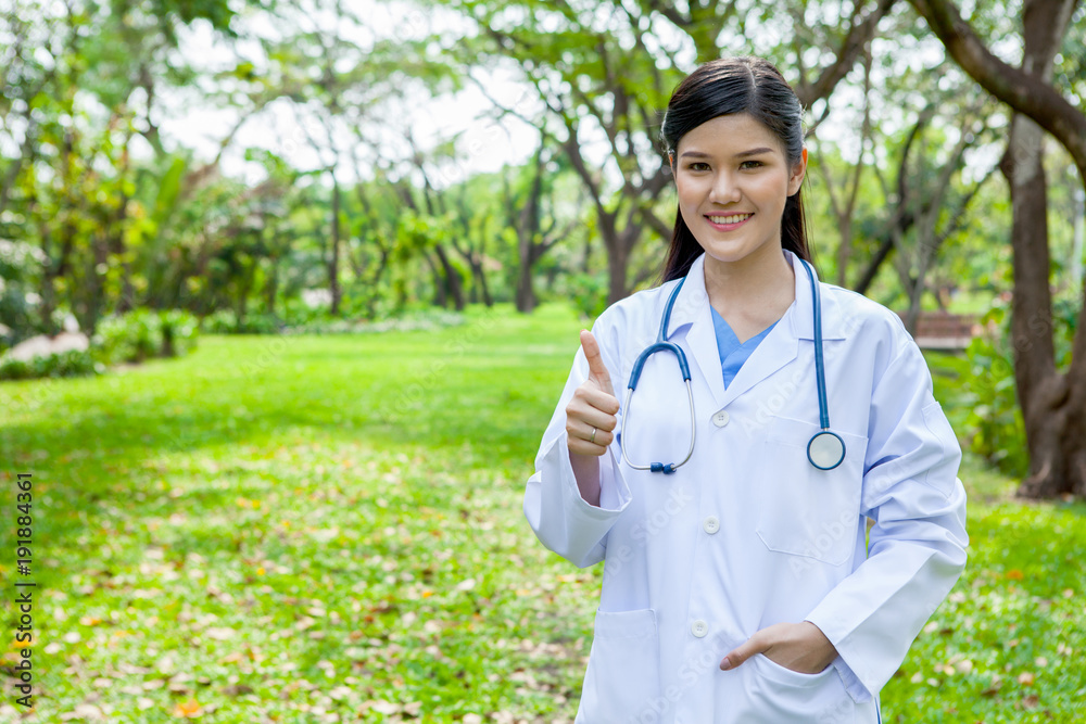 Portrait of a confident female doctor showing thumbs up in garden outdoor Portrait of a confident female doctor showing thumbs up in garden outdoor