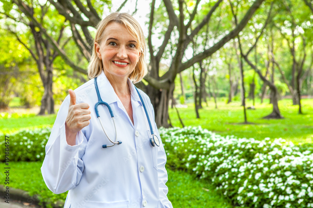 Portrait of a confident female doctor showing thumbs up in garden outdoor Portrait of a confident female doctor showing thumbs up in garden outdoor