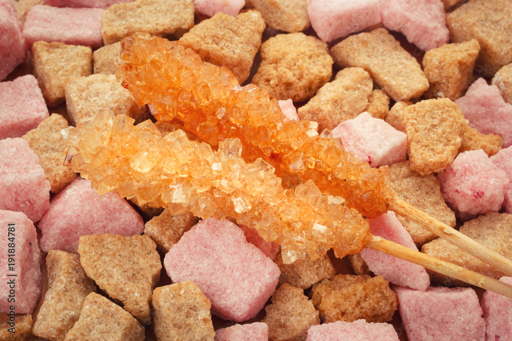 Two cane sugar crystal sticks on lump chopped sugar background Two cane sugar crystal sticks on lump chopped sugar background