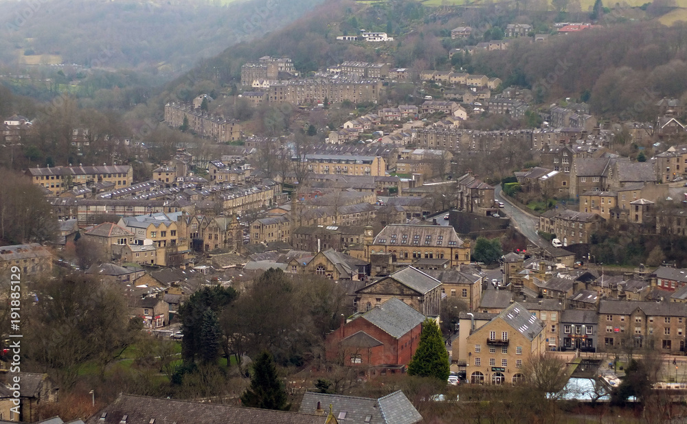 panoramic view of the town of hebden bridge showing the main roads, houses and streets with mill chimneys in winter