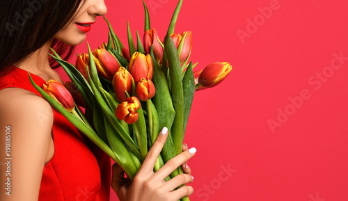 Beautiful woman with bouquet of tulip flowers in red dress