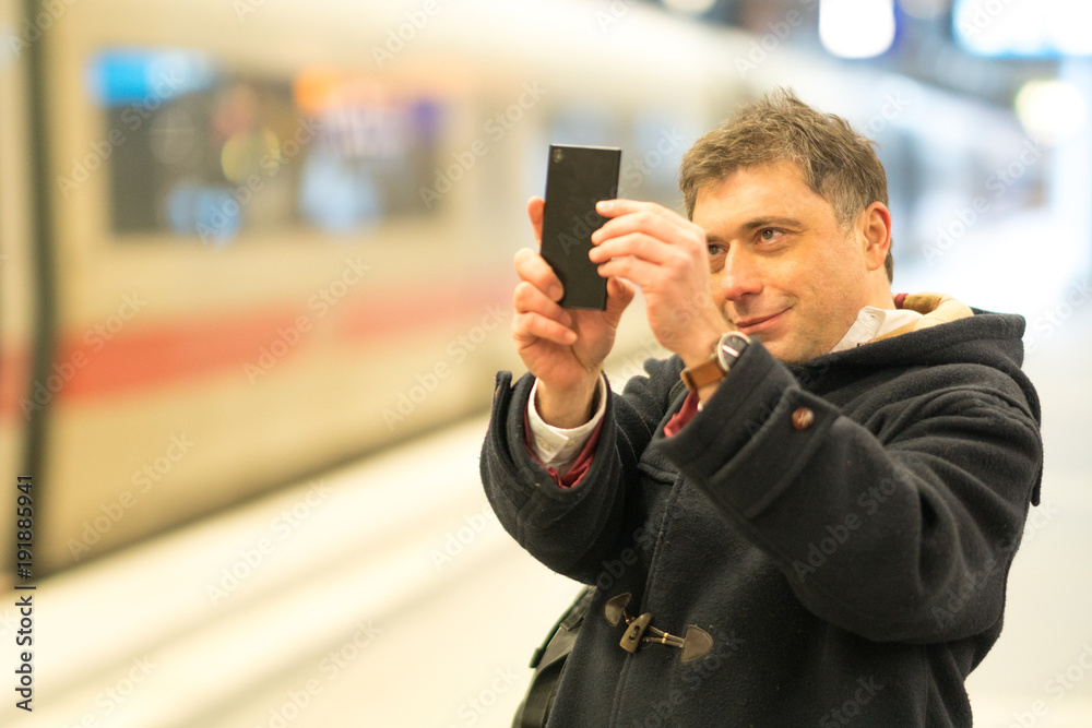 Passenger taking photos with his smartphone from railway station platform Passenger taking photos with his smartphone from railway station platform