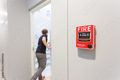 The man running open emergency exit door is and fire alarm on the wall next to the door.