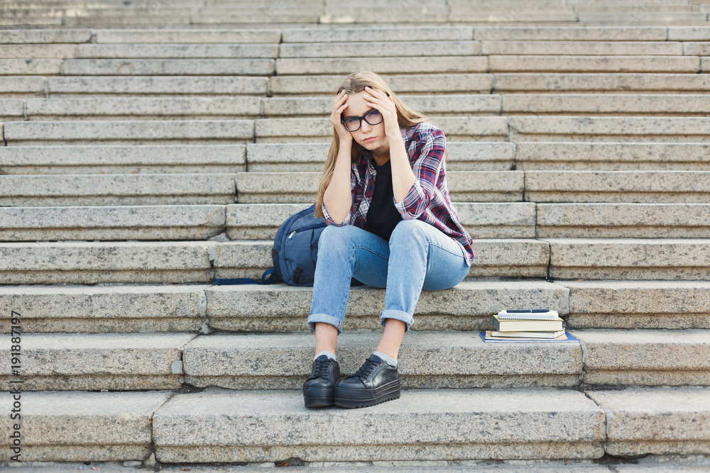 Desperate student sitting on stairs outdoors