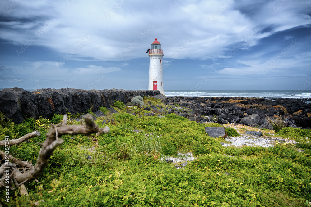 Griffiths Island Lighthouse, Port Fairy, Australia with rocks and grass