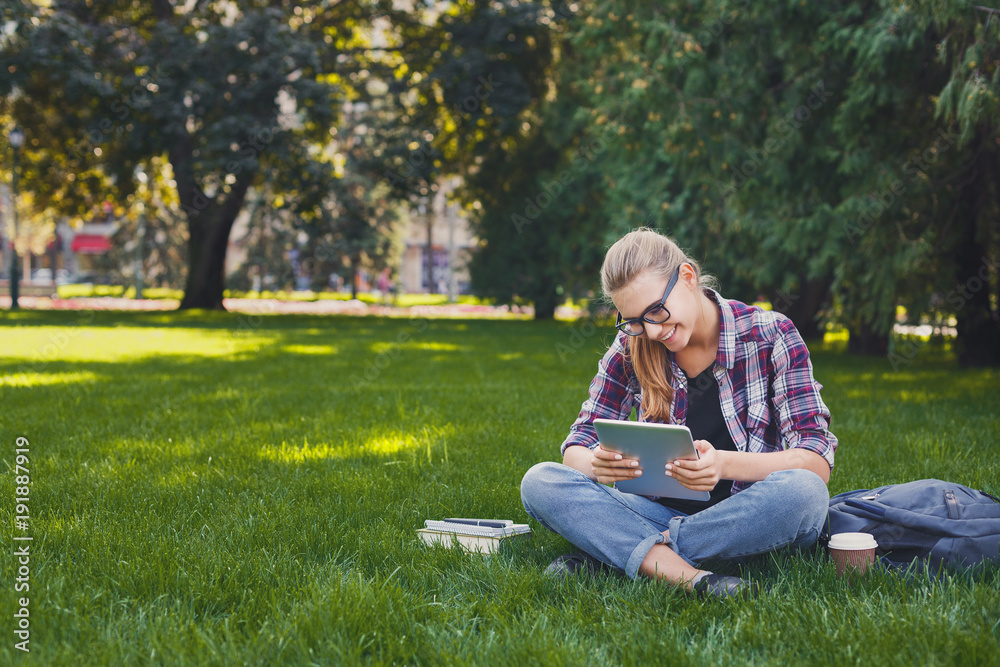 Happy young woman using digital tablet in park Happy young woman using digital tablet in park