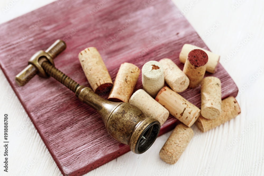 Metal retro corkscrew and heap used wine corks on wooden table. Copy space. Top view. Flat lay.