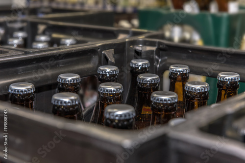 View into a beer crate standing in a beverage market. Crate with full beer bottles. Focus on the bottles. Concept: drinks