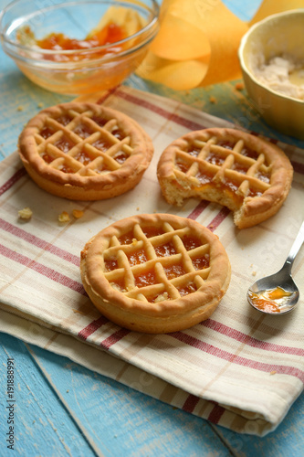 small pies with ingredients around on light blue table