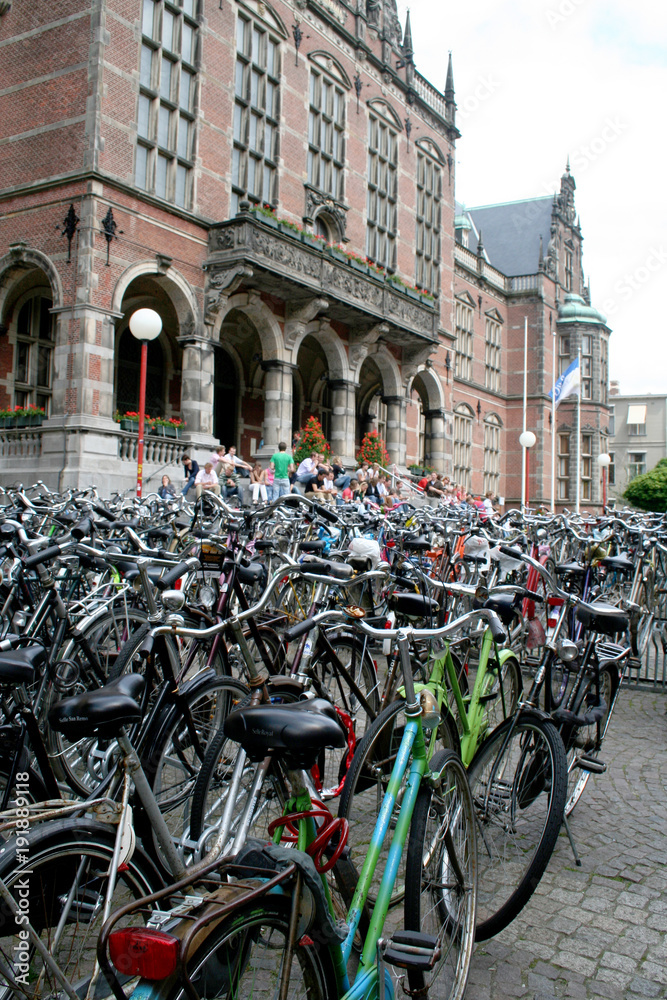 Many bicycles are parked in front od the historic University building in the Centre