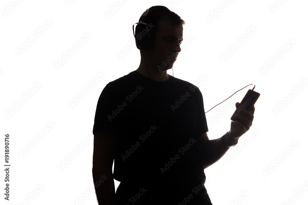 Silhouette of a young man with a smartphone with headphones Silhouette of a young man with a smartphone with headphones
