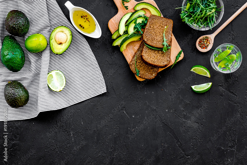 Breakfast for safety weight loss. Avocado toast with rye bread, lime, olive oil and greens on black background top view space for text Breakfast for safety weight loss. Avocado toast with rye bread, lime, olive oil and greens on black background top view space for text