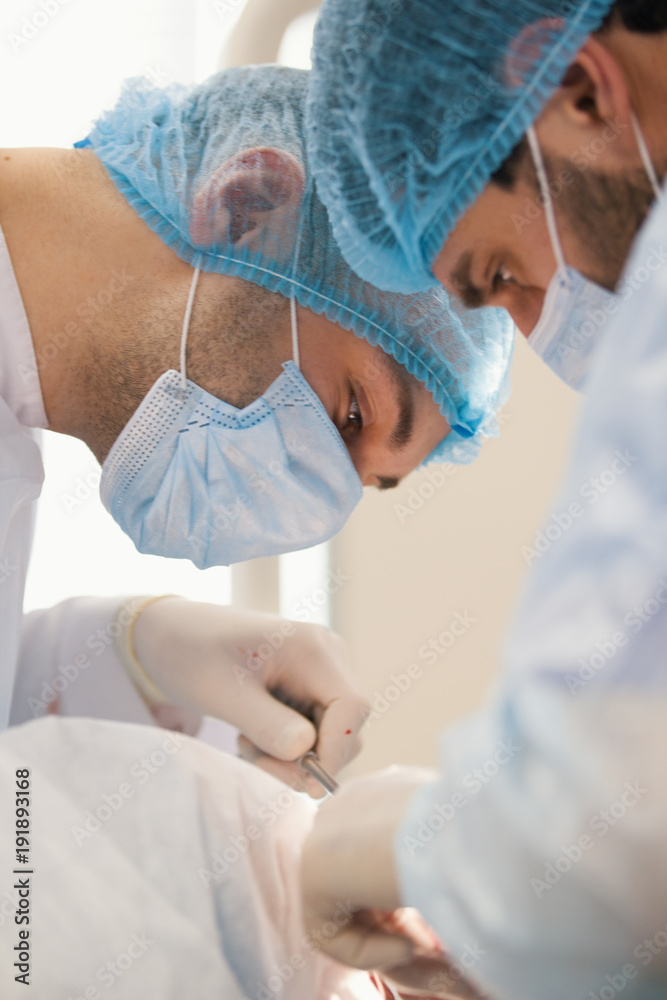 Two surgeons in blue robes make operation in surgery room Two surgeons in blue robes make operation in surgery room