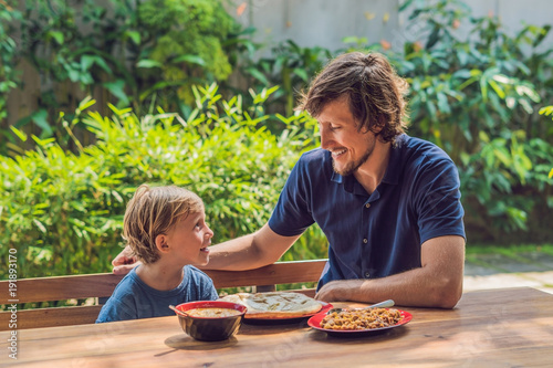 Father and son try Indian food in a cafe on the street photo