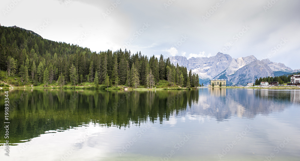 lake in the Alps where mountain peaks and fir woods are reflected