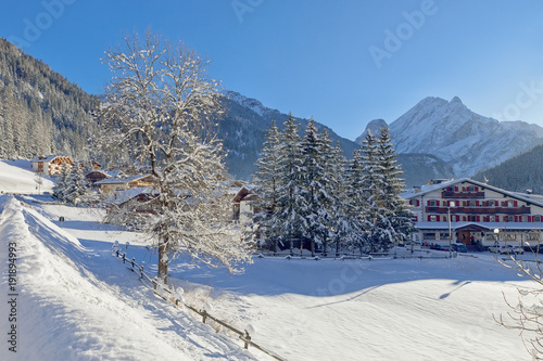 Snowy alpine village in Italy illuminated by sun with mountains in the background. Italian Dolomites, Trentino-Alto-Adige region, Italy © Yamagiwa