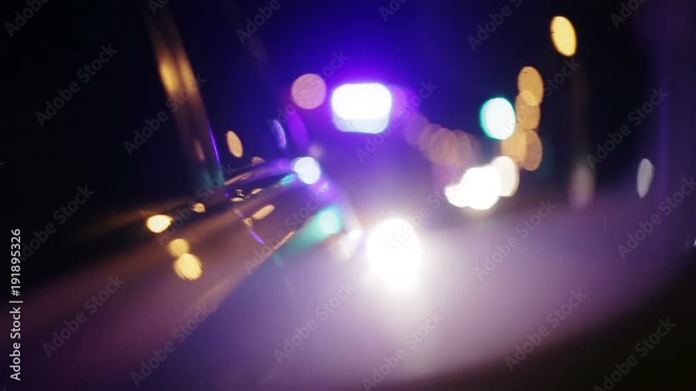 Police lights flashing in side view mirror of car