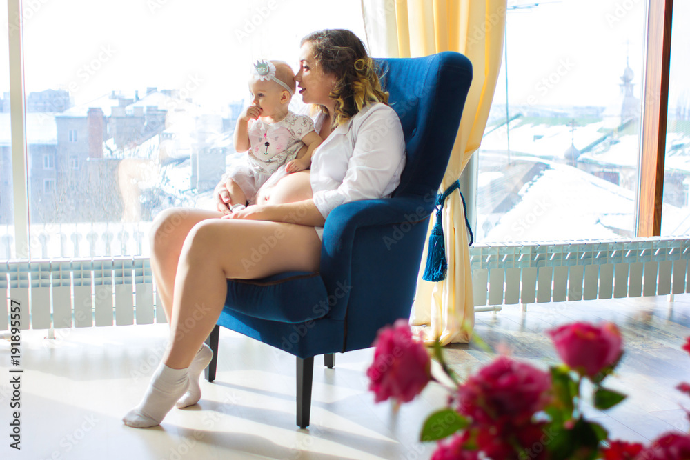 Pregnant mother sits in a chair with the child