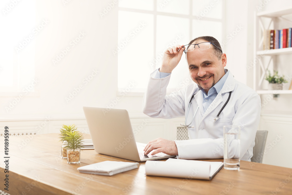 Portrait of doctor in glasses sitting at the desktop