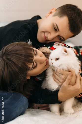 Portrait of a young couple posing with white cat in a cosy room
