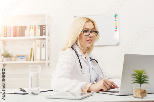 Portrait of female doctor sitting at the desktop © Prostock-studio