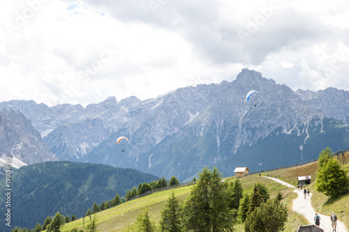 paragliding in the Italian Alps with tourists coming down the valley