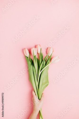 Woman hand hold pink tulip flowers on pink background. Flat lay, top view festive spring flower concept. © Floral Deco