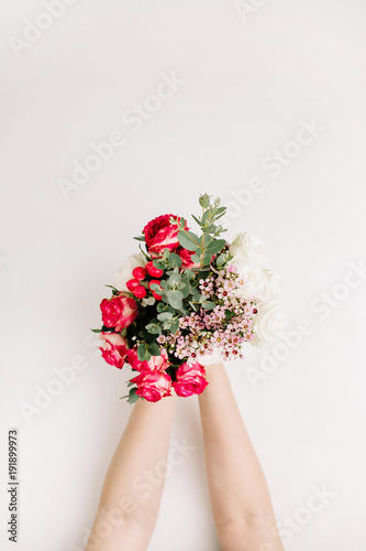 Fototapeta Naklejka Na Ścianę i Meble -  Woman hands hold bouquet of rose flowers, eucalyptus branch, wildflowers. Flat lay, top view spring background.