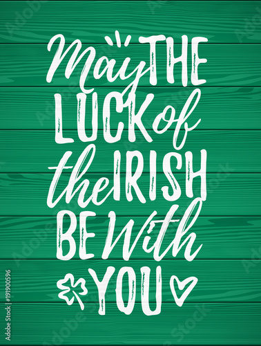 May The Luck Of The Irish Be With You handdrawn dry brush style lettering on green wooden background, 17 March St. Patrick's Day celebration. Suitable for greeting card design, poster, etc.