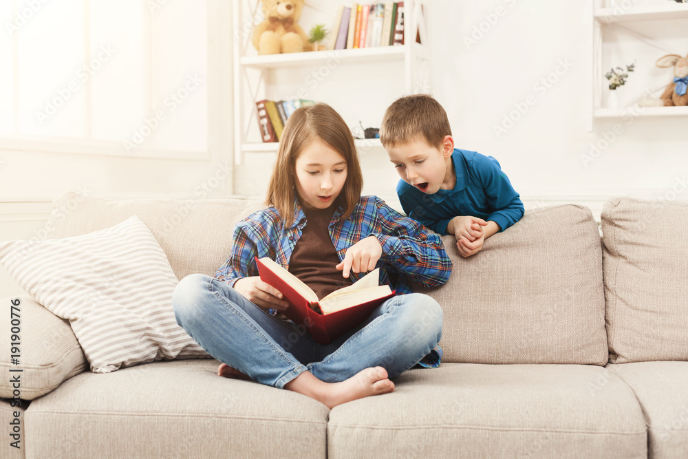 Young girl reading book for her brother