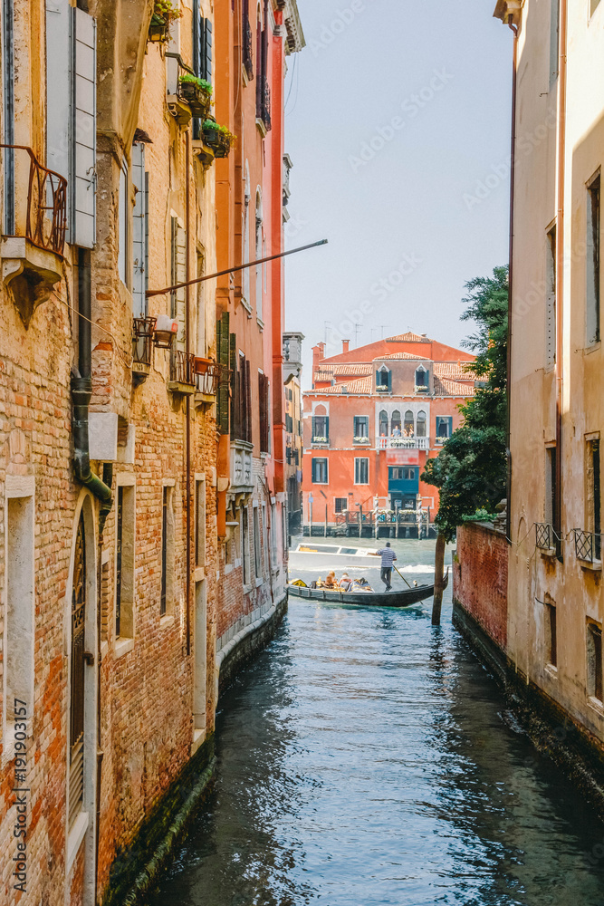 Narrow street-channels and gondolas with tourists in Venice, Italy