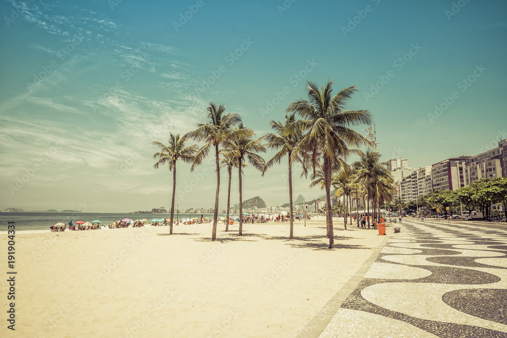 Sunny day on Copacabana Beach with palm trees in Rio de Janeiro, Brazil. Vintage colors