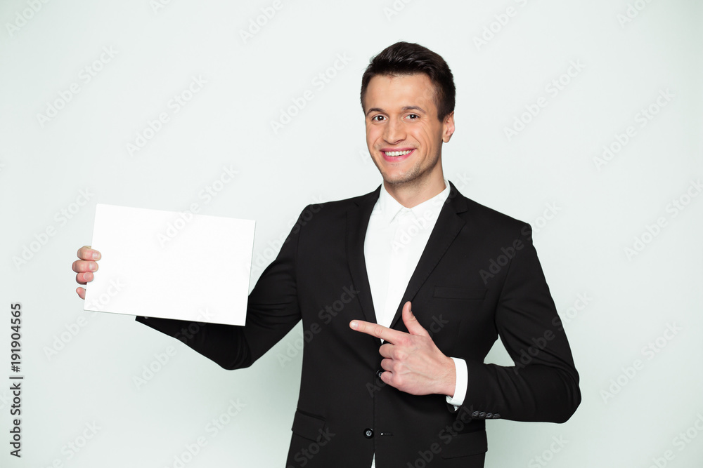 Place for your advertising. A modern handsome stylish smiling young businessman with a white board in his hands. Place for your advertising. A modern handsome stylish smiling young businessman with a white board in his hands.