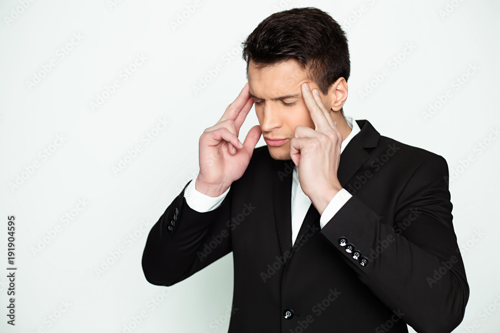 Severe migraine. Portrait of a young serious man in a black suit who holds his head through severe pain. Severe migraine. Portrait of a young serious man in a black suit who holds his head through severe pain.