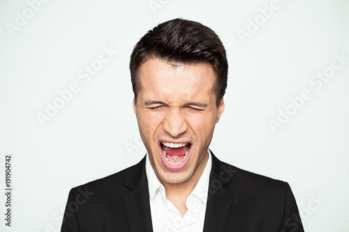 I've had enough. Portrait of a screaming and angry young businessman with arms raised yelling at the camera.