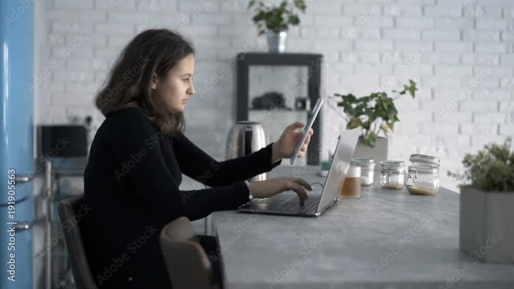 Teenage girl using laptop and tablet sitting by table at home
Teenage girl using laptop and tablet sitting by table at home