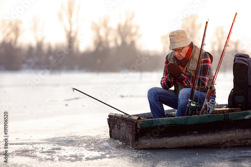 Winter season- man fishing on the frozen river