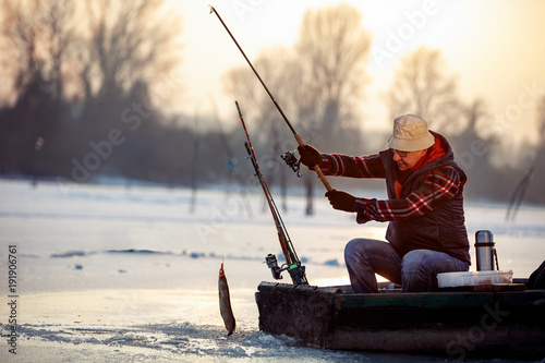ice fishing on frozen lake- smiling fisherman catch fish pike