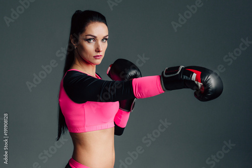 Close up portrait of a young sportswoman in boxing gloves. Pretty female brunete boxer. Healthy lifestyle concept. Girl fighter. © beatleoff