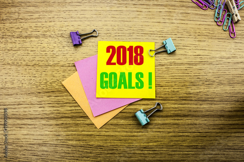 2018 goals on yellow sticky note, on wooden background. New Year resolutions concept. photo