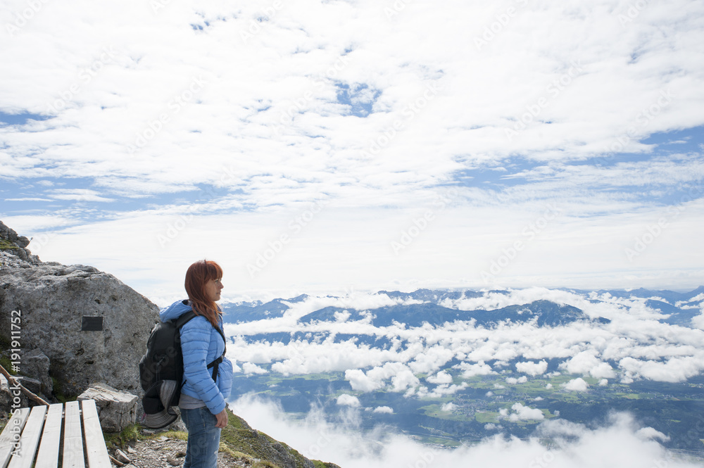 woman who looks at the view from above. There are mountains wrapped in clouds woman who looks at the view from above. There are mountains wrapped in clouds
