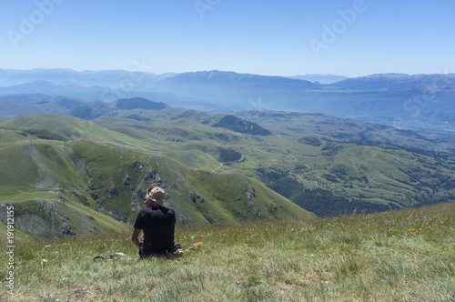 man sitting on the grass looking at the mountains of the Apennines © Stefania