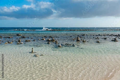 pebble beach and ocean waves on the sea of the Caribbean island of Aruba