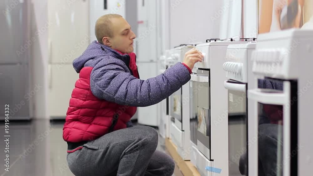 Buyer chooses a stove in the kitchen at a home appliance store Buyer chooses a stove in the kitchen at a home appliance store