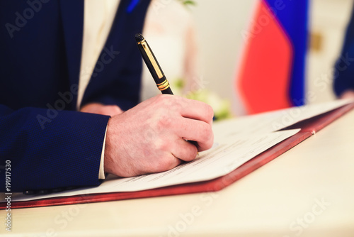 Hand with a pen signs the document with a shallow depth of field
