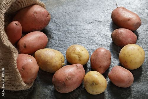 Red Potatoes from burlap sack on slate table with copy space